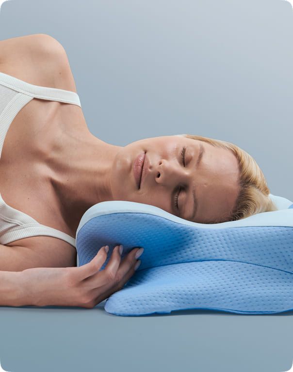 A side sleeper's head resting in the central hollow of the pillow with the neck ridge under the neck