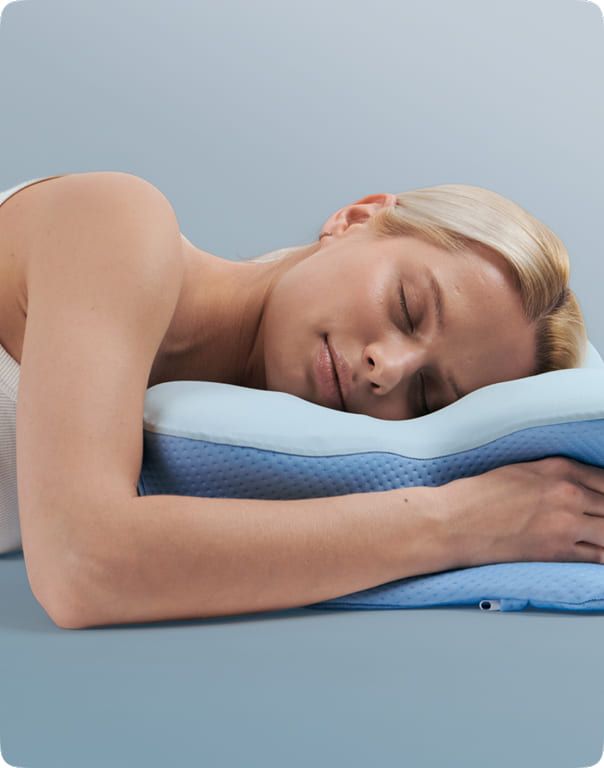 A sleeper resting face down towards the lower edge of the pillow with an arm tucked under the wing